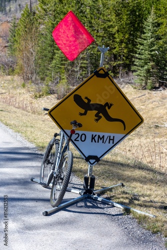 Bicycle Parked on Road Shoulder. Salamander Lizard Traffic Speed Limit Yellow Sign. Cycling Bow Valley Parkway Road in Canada Banff National Park photo