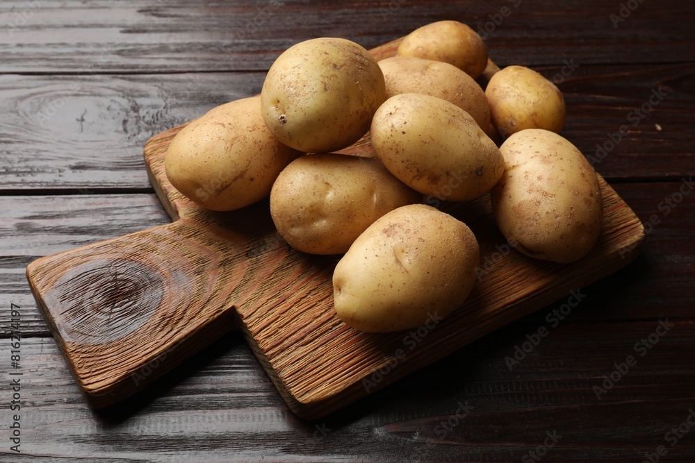 Raw fresh potatoes and cutting board on wooden table Raw fresh potatoes and cutting board on wooden table