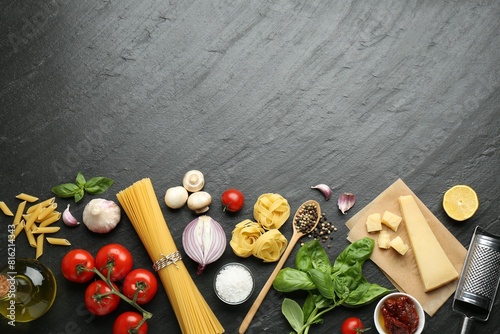 Different types of pasta, spices, garter and products on dark textured table, flat lay. Space for text photo