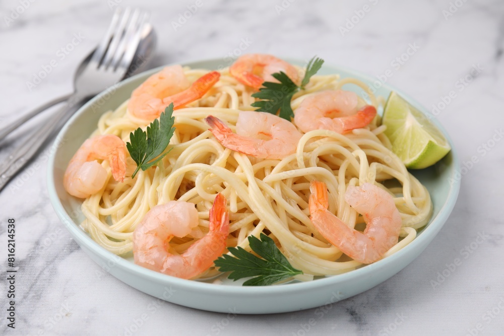 Tasty spaghetti with shrimps, lime and parsley on white marble table, closeup Tasty spaghetti with shrimps, lime and parsley on white marble table, closeup