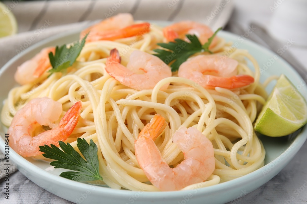Tasty spaghetti with shrimps, lime and parsley on table, closeup