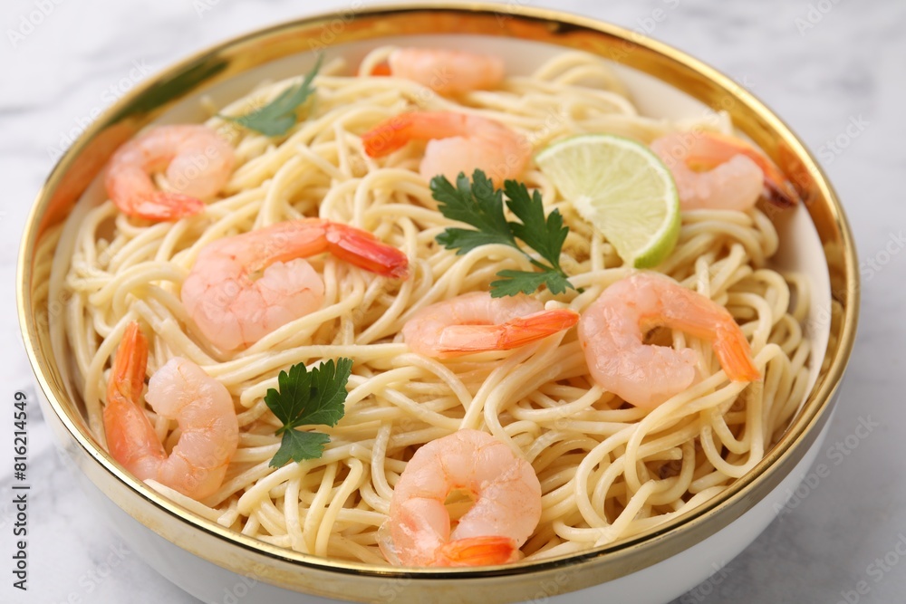 Tasty spaghetti with shrimps, lime and parsley in bowl on white table, closeup Tasty spaghetti with shrimps, lime and parsley in bowl on white table, closeup
