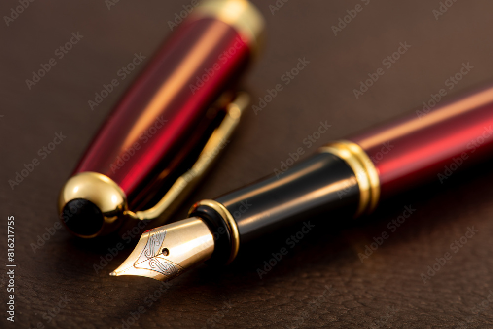Red fountain pen on leather surface, selective focus Red fountain pen on leather surface, selective focus