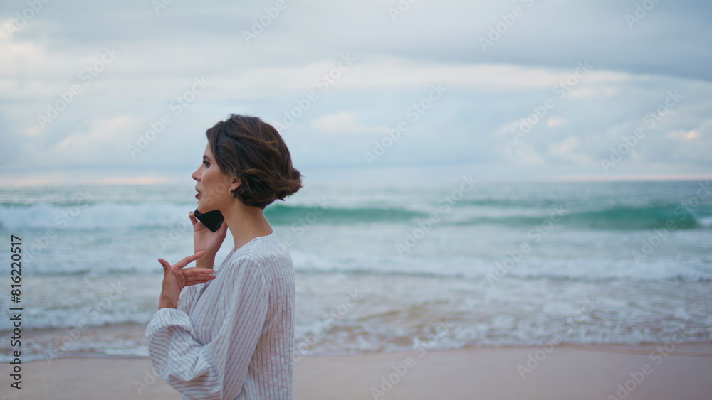 Woman enjoying cellphone conversation at ocean waves. Calm model stepping beach Woman enjoying cellphone conversation at ocean waves. Calm model stepping beach