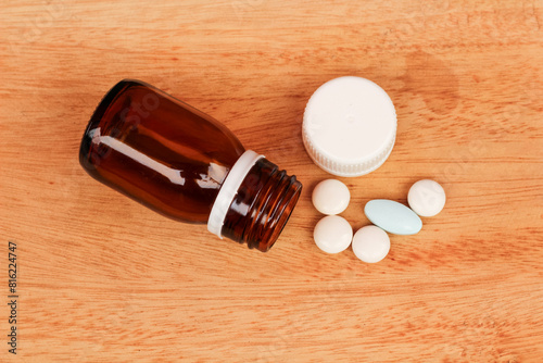 pills and bottle. medicine granules or pills spilling out of a bottle on a wooden textured background. photo