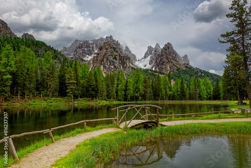 Green lake in the heart of the Dolomite Mountains. Moody landscape with turquoise water alpine lake Lago di Dobbiaco in Dolomites mountains, Cortina dAmpezzo, Italy on cloudy spring day. Lake Toblache photo