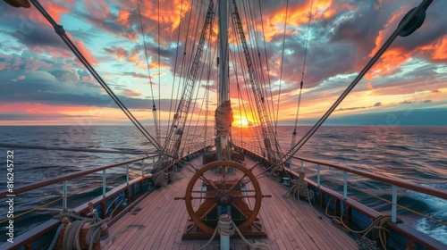 Deck view with ship wheel from a sailing ship with beautiful seascape at sunset.