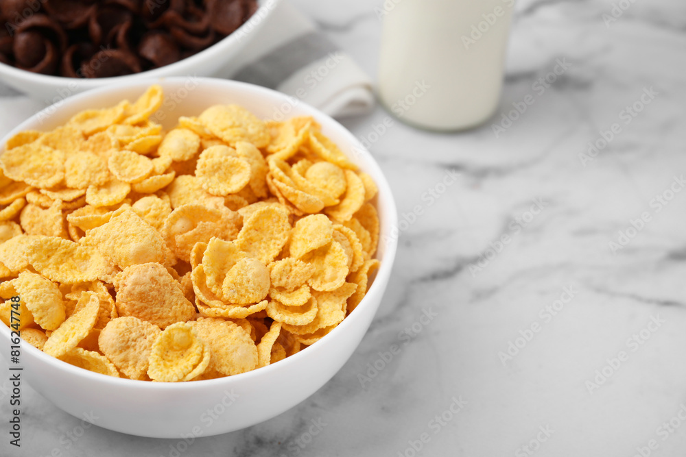 Breakfast cereal. Tasty crispy corn flakes in bowls on white marble table, closeup. Space for text Breakfast cereal. Tasty crispy corn flakes in bowls on white marble table, closeup. Space for text