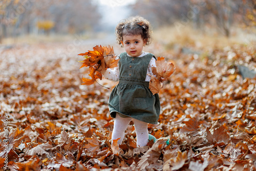 Obraz na płótnie Among autumn s leaves. Cute astonished little girl holding leaves, surrounded by the season s fallen beauty w salonie