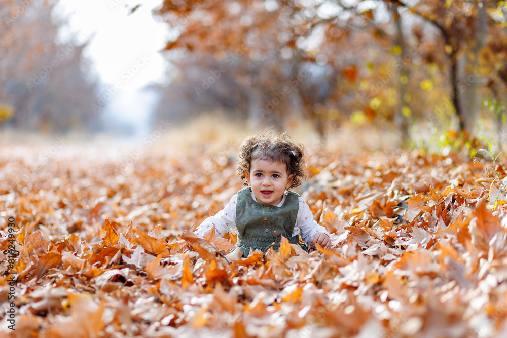 Curly hair child playing among the rustling autumn leaves