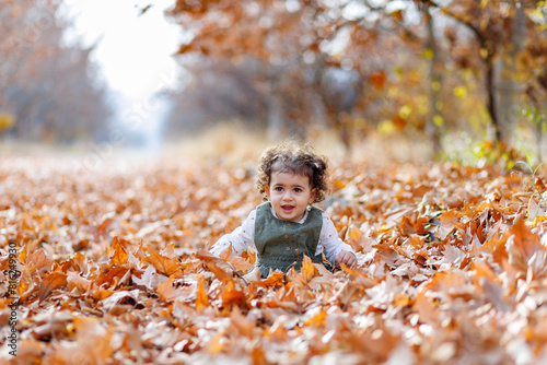 Obraz na płótnie Curly hair child playing among the rustling autumn leaves w salonie