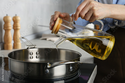 Vegetable fats. Woman pouring cooking oil into frying pan on stove in kitchen  closeup