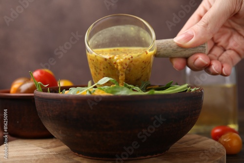 Photos Woman pouring tasty vinegar based sauce (Vinaigrette) into bowl with salad at wo