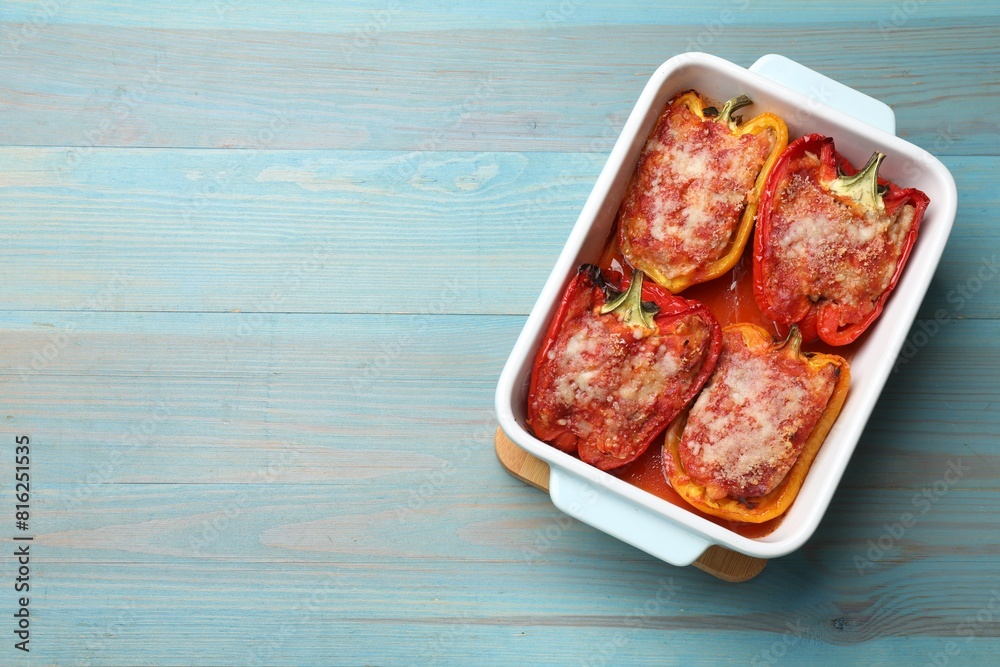 Tasty stuffed peppers in dish on light blue wooden table, top view. Space for text Tasty stuffed peppers in dish on light blue wooden table, top view. Space for text