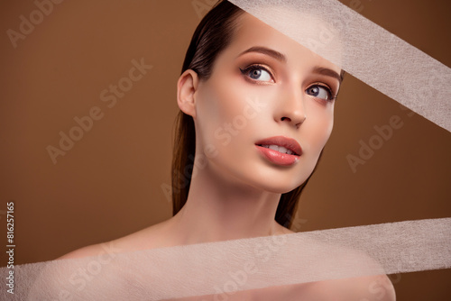 Photo of dreamy adorable lady naked shoulders applying body lifting stripes isolated brown color background photo