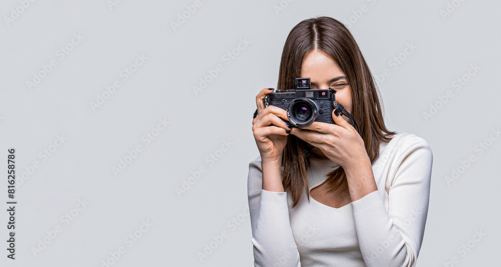 Beautiful young woman photographing on retro camera isolated on gray background. Professional photographer working. Girl using a camera photo. Girl with a cameras Beautiful young woman photographing on retro camera isolated on gray background. Professional photographer working. Girl using a camera photo. Girl with a cameras