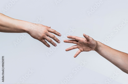 Two male hands reaching towards each other on isolated gray background. Helping hand outstretched, isolated arm, salvation. Close up help hand. Two hands, helping arm friend, teamwork. Helping hand photo