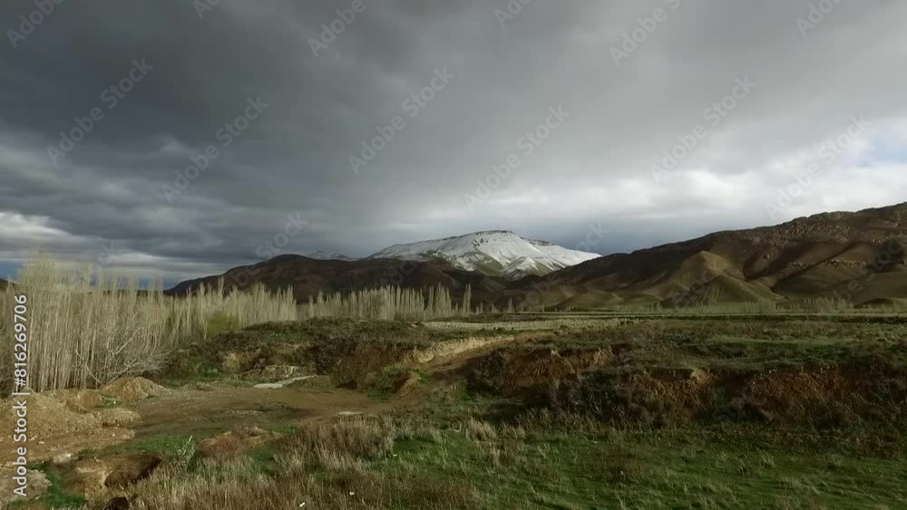 Extreme Wide Shot of lush green hills and plains with a snow capped mountain in the distance, showcasing the transition from winter to spring and the natural beauty of the landscap. Extreme Wide Shot of lush green hills and plains with a snow capped mountain in the distance, showcasing the transition from winter to spring and the natural beauty of the landscap.