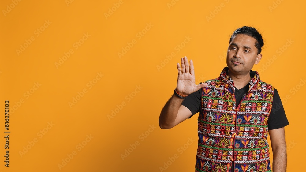 Indian man trying to stop chaotic fight using calming hand gesture to diffuse tensions, doing peaceful resolution. Reassuring person doing calm down sign gesturing, studio background, camera A Indian man trying to stop chaotic fight using calming hand gesture to diffuse tensions, doing peaceful resolution. Reassuring person doing calm down sign gesturing, studio background, camera A