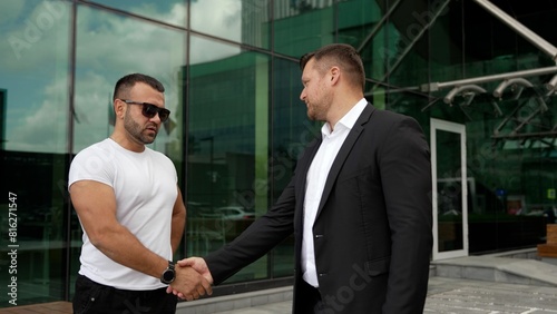 Business concept. Male strong handshake. A businessman in a suit and an athlete in a T-shirt shake hands. Business men shaking hands.