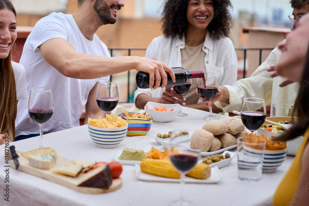 Shot of a table with food and alcoholic beverages where a group of unrecognizable people drink wine and eat at a lunch party on an outdoor terrace celebrating an event during the summer holidays