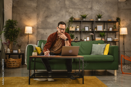 Adult caucasian man sit on sofa and work from home on lap top © Miljan Živković