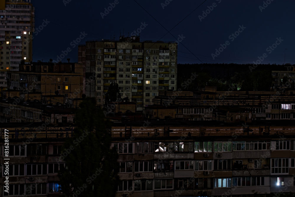 View on a panel residential buildings during blackout of electricity at night. Dark blue sky and forest on a background. Kyiv, Ukraine. Consequences after russian missile attacks. View on a panel residential buildings during blackout of electricity at night. Dark blue sky and forest on a background. Kyiv, Ukraine. Consequences after russian missile attacks.