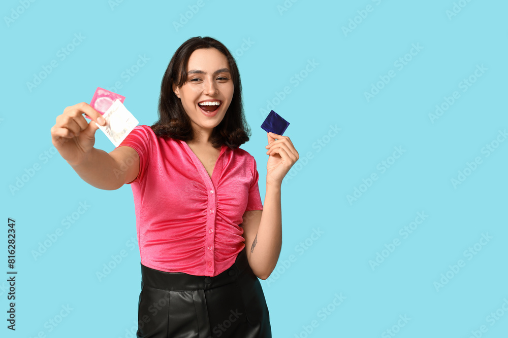 Young woman with condoms on blue background. Safe sex concept Young woman with condoms on blue background. Safe sex concept
