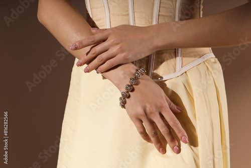 Beautiful young woman in dress with stylish bracelet on beige background