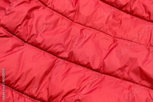 Red waterproof winter puffer jacket close up. Polyester fabric textile