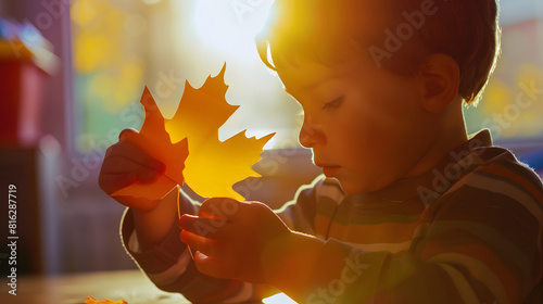 Boy in early development class cut paper and glue holding paper maple leaf : Generative AI photo