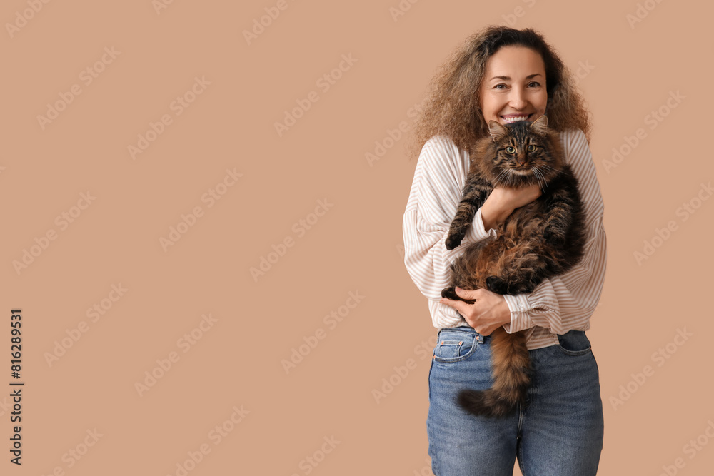 Happy mature woman with cute cat on brown background