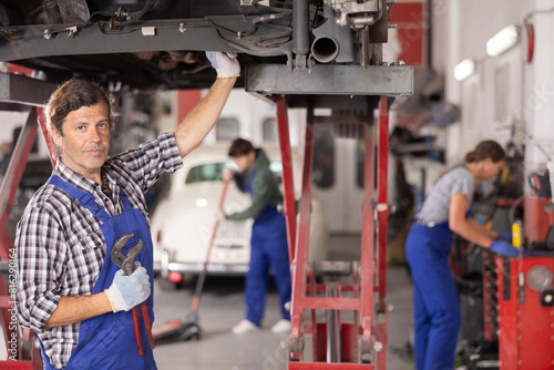 Experienced auto mechanic doing an inspection of rear suspension of a car in a car service center photo