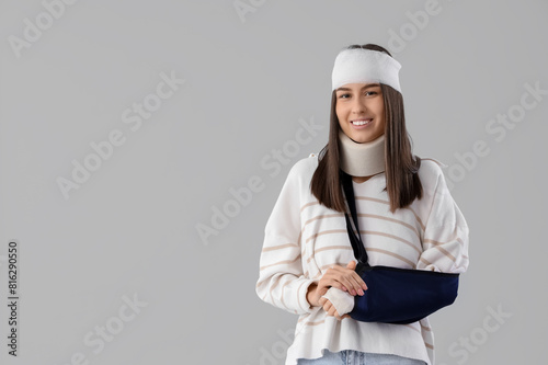 Injured young woman after accident with broken arm on light background