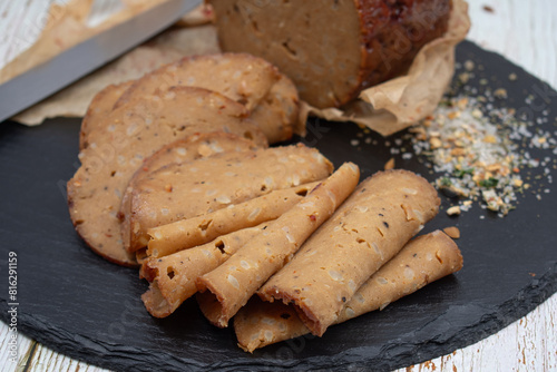 Seitan shaped and cooked in ham press, sliced on slate board. Vegan protein, plant based alternative to meat.