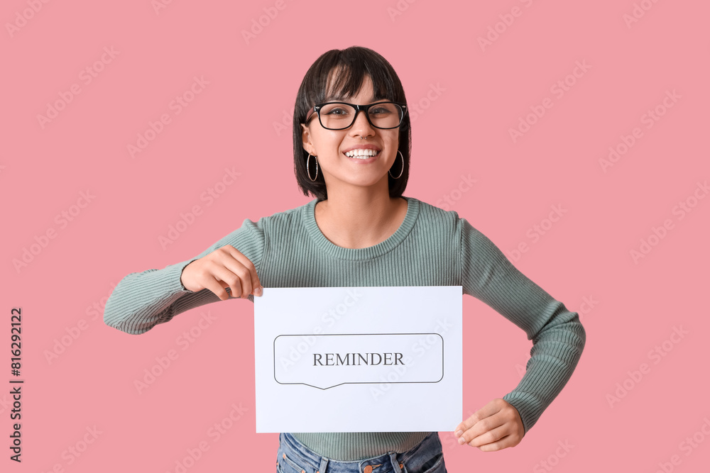 Pretty young woman holding speech bubble with text REMINDER on pink background Pretty young woman holding speech bubble with text REMINDER on pink background