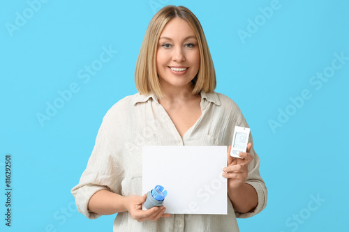 Woman with glucose sensor applicator, glucometer and blank paper on blue background. Diabetes concept