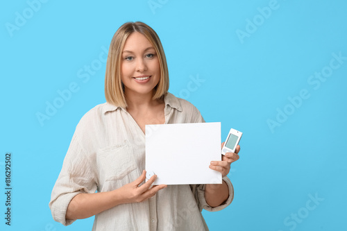 Woman with glucometer, sensor for measuring blood sugar level and blank paper on blue background. Diabetes concept
