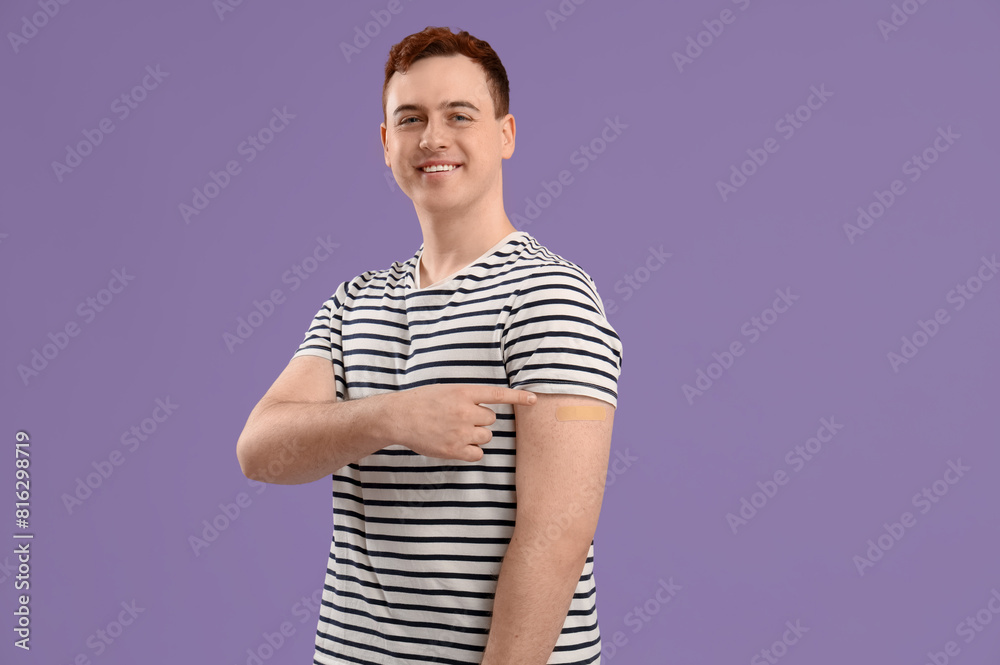 Obraz premium Young man with applied medical patch on purple background. Vaccination concept