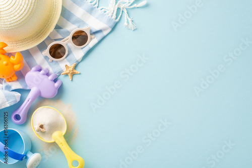 Top view of summer beach accessories laid out on a striped towel including a sun hat, sunglasses, sand toys, and a starfish