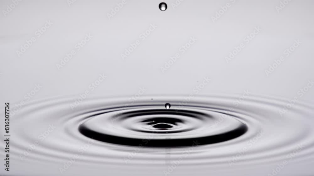 A single drop of water falling into a pool of water in slow motion.