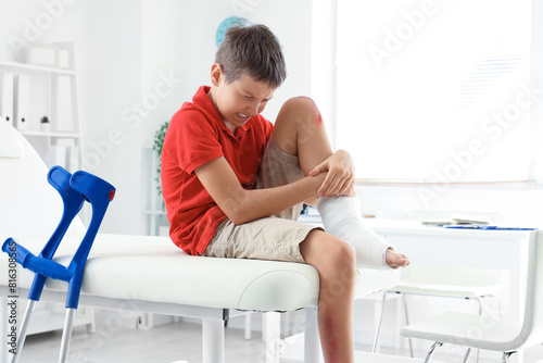 Little boy with wounded knee sitting on couch in clinic