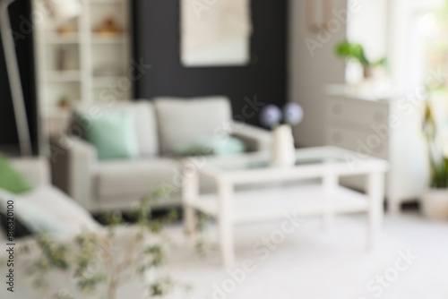 Blurred view of modern living room with grey sofa and glass coffee table © Pixel-Shot
