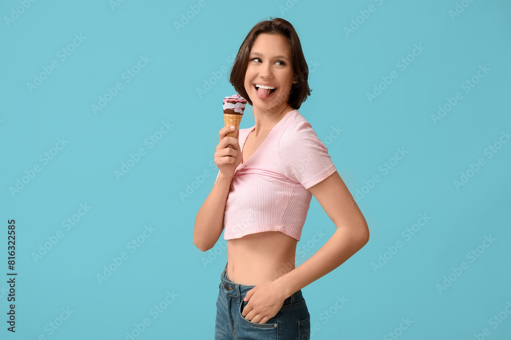 Beautiful young woman with sweet ice-cream in waffle cone showing tongue on blue background Beautiful young woman with sweet ice-cream in waffle cone showing tongue on blue background