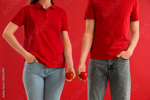 Blood donors with applied patches and grip balls on red background, closeup photo