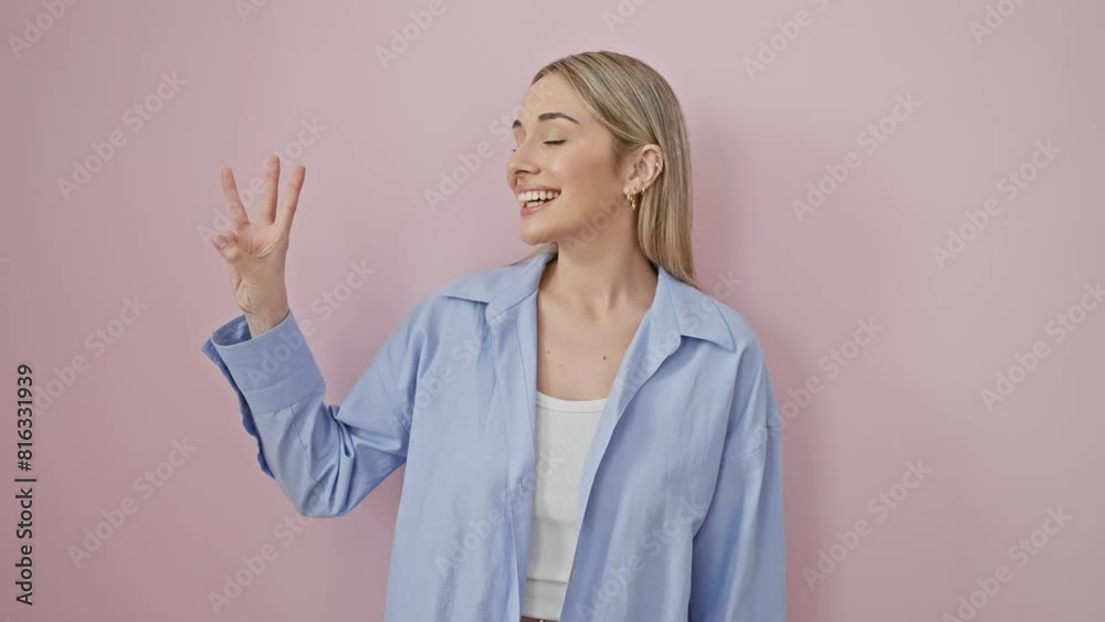 Cheerful blonde lass in a shirt, confidently pointing up, showing number three with her fingers over an isolated pink backdrop Cheerful blonde lass in a shirt, confidently pointing up, showing number three with her fingers over an isolated pink backdrop