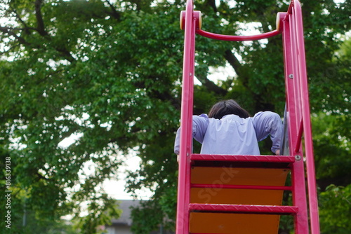 公園の滑り台で遊んでいる小学3年生の女の子の後ろ姿。