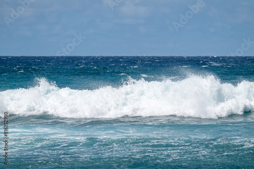 White foam and spray of a crashing wave on the beautiful blue clean Pacific Ocean off the coast of Maui  Hawaii  as a nature background 