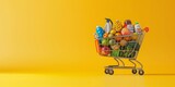 A shopping cart full of food and goods on a yellow background with copy space for a banner design.