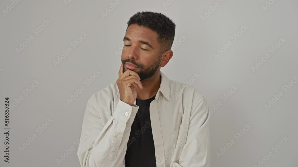 Young african american man, standing, wearing a shirt, thoughtfully pondering a serious question with hand on chin, over an isolated white background Young african american man, standing, wearing a shirt, thoughtfully pondering a serious question with hand on chin, over an isolated white background